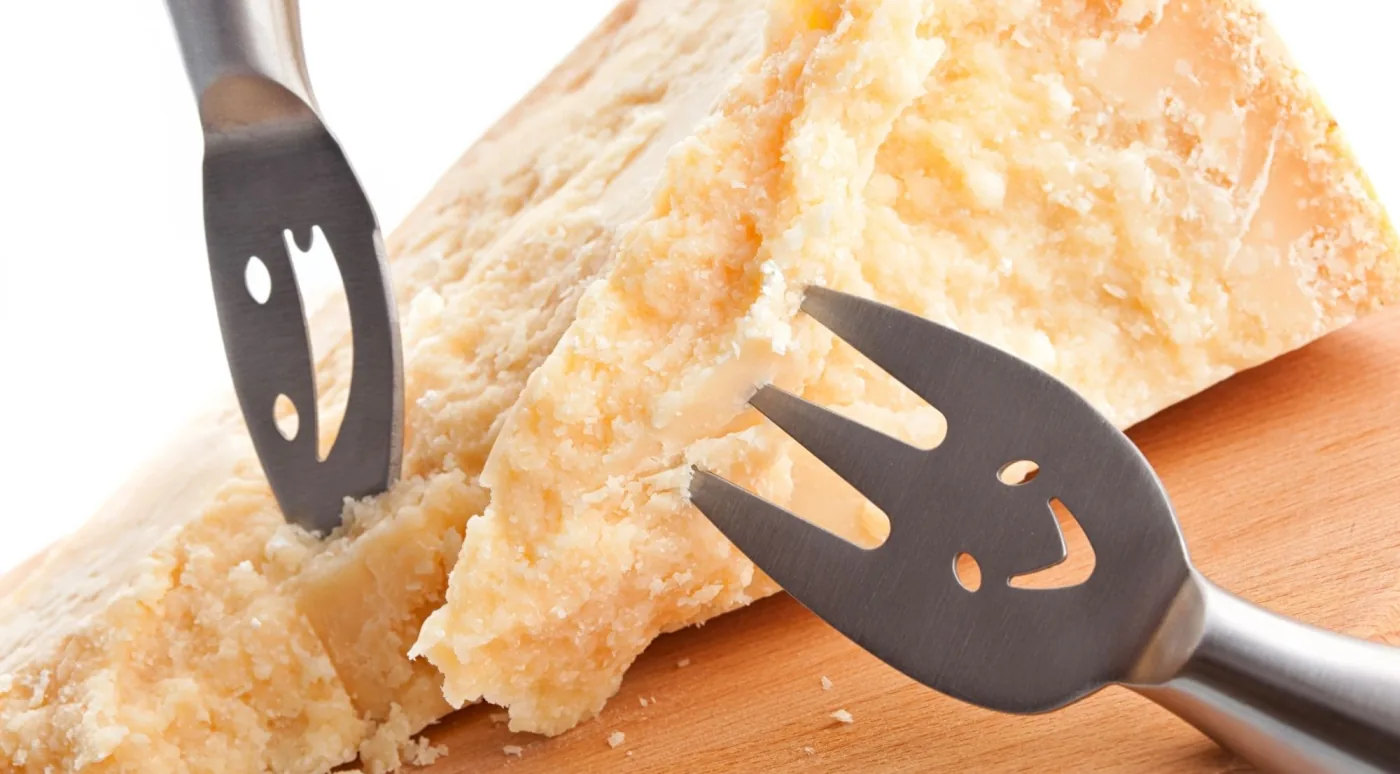 A wheel of Parmigiano Reggiano split open with the traditional almond-shaped cheese knives, the centrepiece of a Food Valley day trip from Bologna